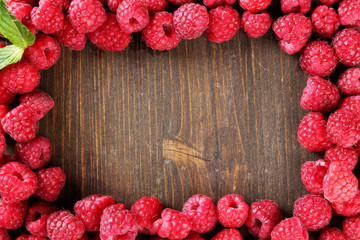 Ripe sweet raspberries on wooden background
