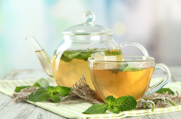 Teapot and cup of herbal tea with fresh mint flowers