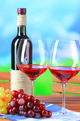 Glasses of wine on napkin on wooden table on nature background