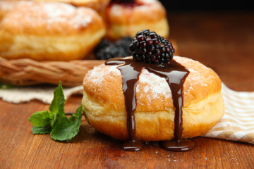 Tasty donuts with chocolate and berries on wooden table