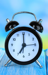 Alarm clock on table on blue background