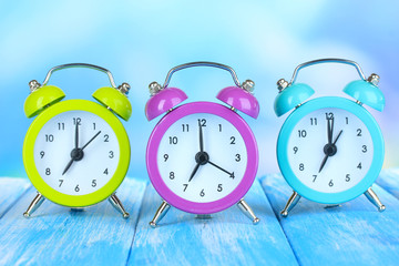 Colorful alarm clocks on table on blue background