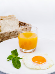 Breakfast consisting of orange juice and fried egg.