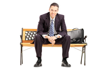 Smiling young businessman sitting on a wooden bench