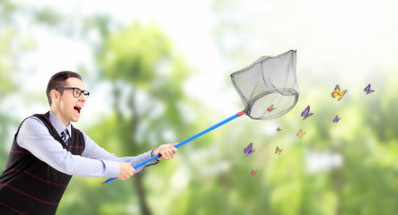 Male catching butterflies with net in a park