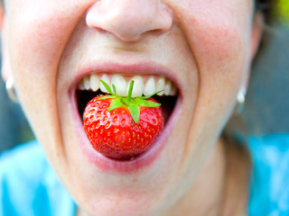 woman is eating a strawberry