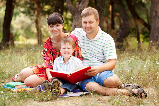 Happy father, mother and son reading book