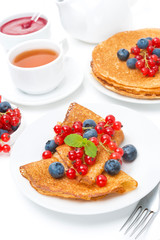 Breakfast with pancakes, fresh berries, jam and black tea