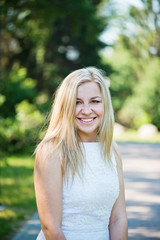 Naklejka premium Beautiful young blond woman in a white dress outdoors