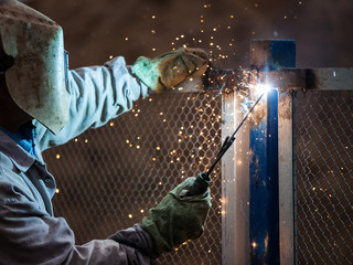 Arc welder worker in protective mask welding metal construction