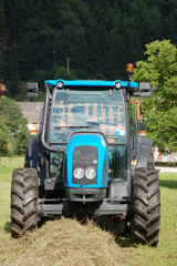 A tractor collecting the hay in a field