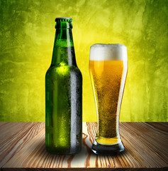Glass of beer and beer bottle on wood table