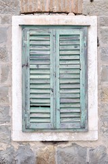 Fototapeta na wymiar The old window with blue closed shutters on a old house