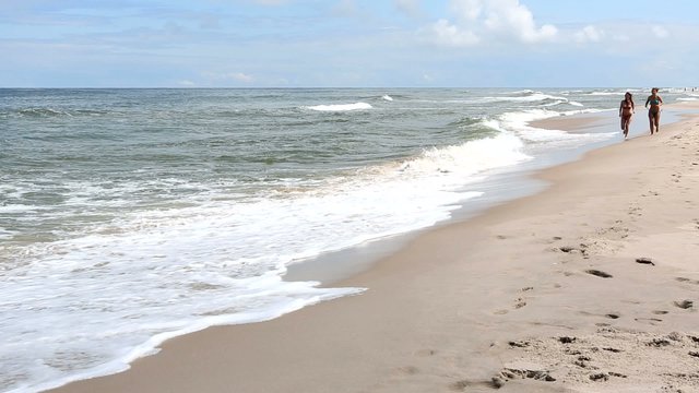 Two beautiful women running on the beach