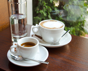 Espresso and cappuccino cups standing on the wooden table