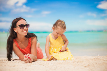 Young mother and her little daughter lying at tropical beach