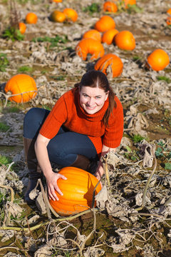Young woman working on pumpkin field