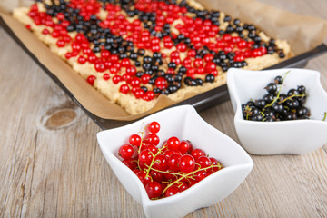 red and black currant berries with home baked cake on background