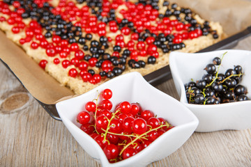 red and black currant berries with home baked cake on background