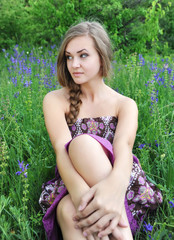 Beautiful young woman in violet flowers outdoors