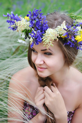 Naklejka premium Beautiful young woman with flower wreath in the grass of feather