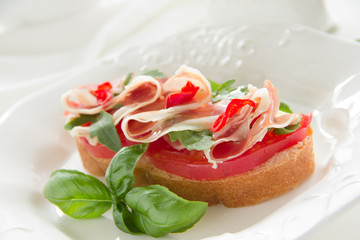 Bruschetta with prosciutto, tomato and basil.
