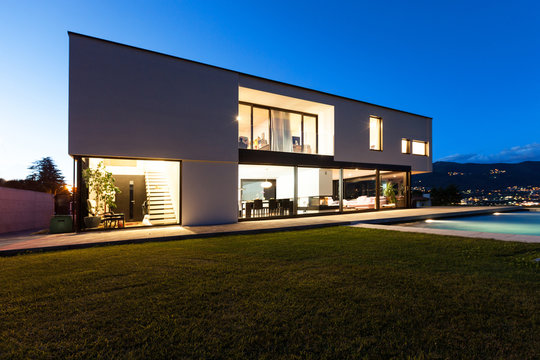 Modern villa with pool, view from garden, night scene