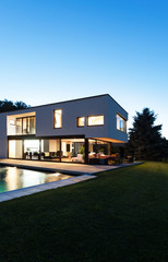 Modern villa with pool, view from garden, night scene
