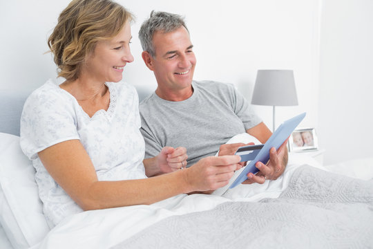 Cheerful couple using their tablet pc to buy online