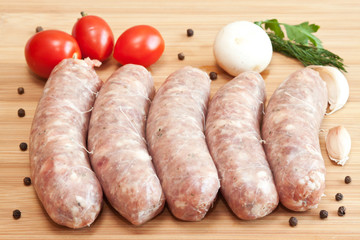 Uncooked sausages with vegetables on the chopping board