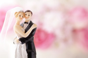 Figurines of wedding cake topper with flowers in background