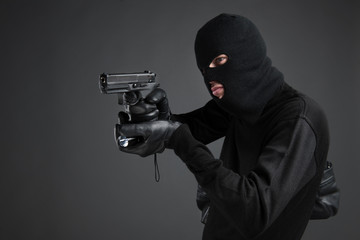 Criminal. Side view of men in black balaclava aiming with a gun