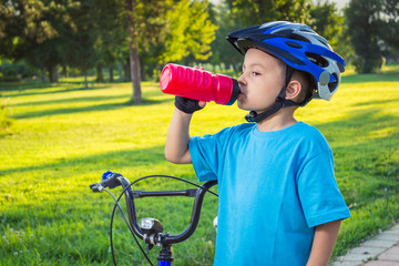 Little boy drinking water by the bike
