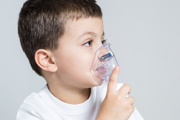 Little boy having inhalation for easing cough