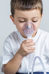 Little boy having inhalation for easing cough