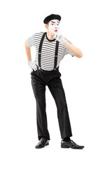 Full length portrait of a male mime artist gesturing silence