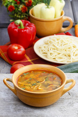 Top view on pot of tomato soup and fresh vegetables on old wood