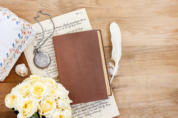 Diary, old letters and red freesia flower on wooden table. Roman