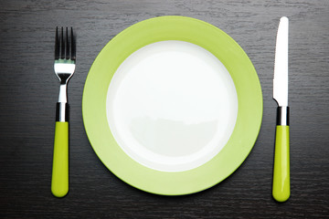 Knife, color plate and fork, on wooden background