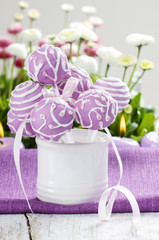 Obraz na płótnie Canvas Liliowy cake pops w białym ceramicznym słoju. Białe i różowe stokrotki