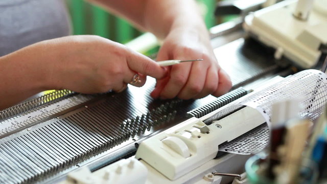 Woman straightens loops on knitting machine