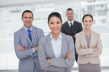 Cheerful work team posing crossing arms