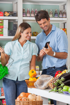 Couple Using Mobilephone While Shopping In Supermarket