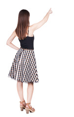 Back view of young brunette woman pointing at wall.