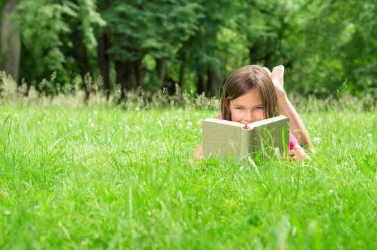 Little Girl in the Gras looking over Book
