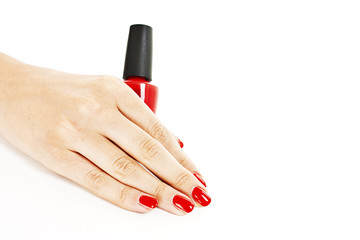 Woman's hand with a bottle of red nail polish