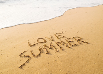 Text "love summer" written in the sand on the beach