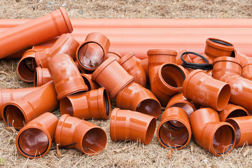 Orange Rohre aus Kunststoff liegen in trockenem Gras