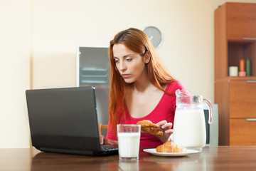 Cute girl checking e-mail in laptop during breakfast time at hom
