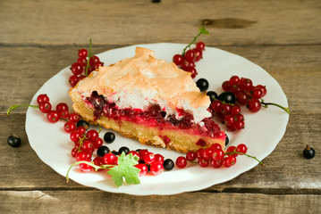 Piece of berry pie with red and black currants on white plate